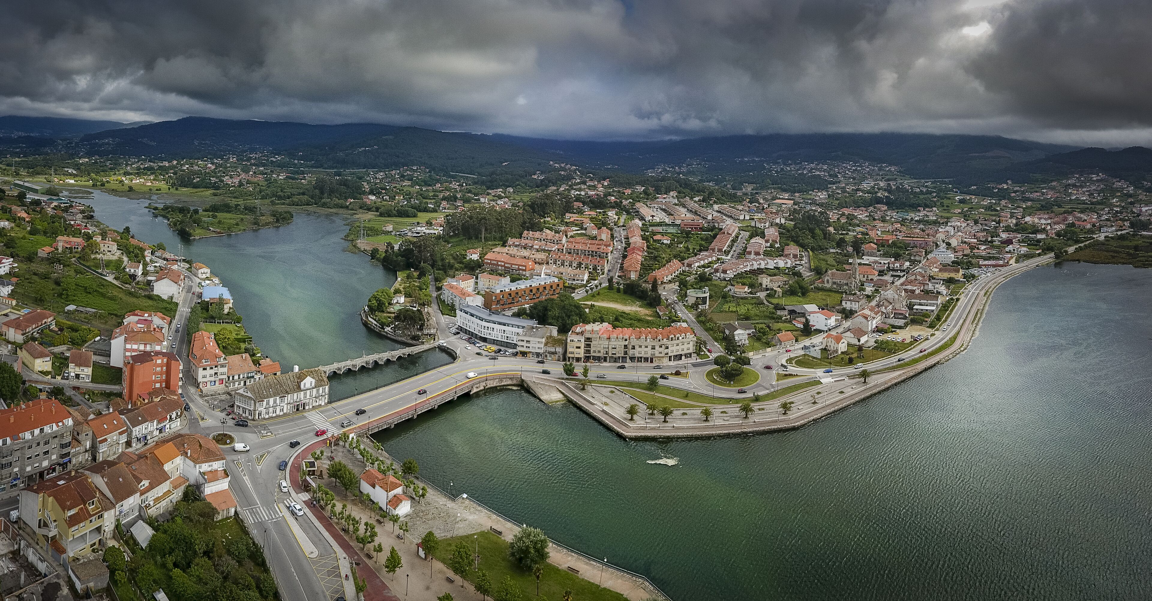An aerial view of a coastal town with a river, bridges, and residential buildings.