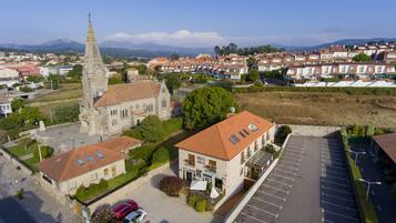 Vista aérea de un pueblo con una iglesia destacada, un hotel y un estacionamiento.