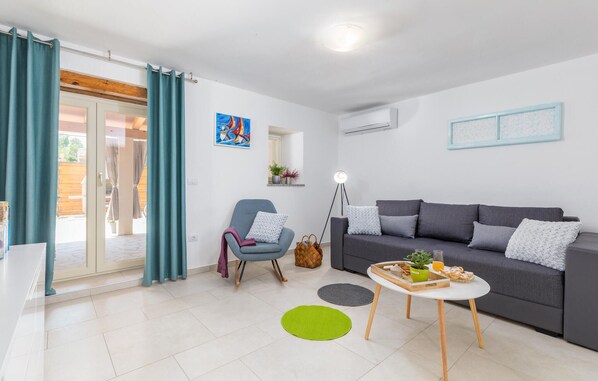 A modern living room with a grey sofa, a blue armchair, a small white table, and a green rug. - Lovely home in Duga Uvala (Duga Uvala)