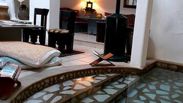 Cozy room with a traditional design, featuring a seating area with a sofa and chairs, a small table, and a bookshelf.