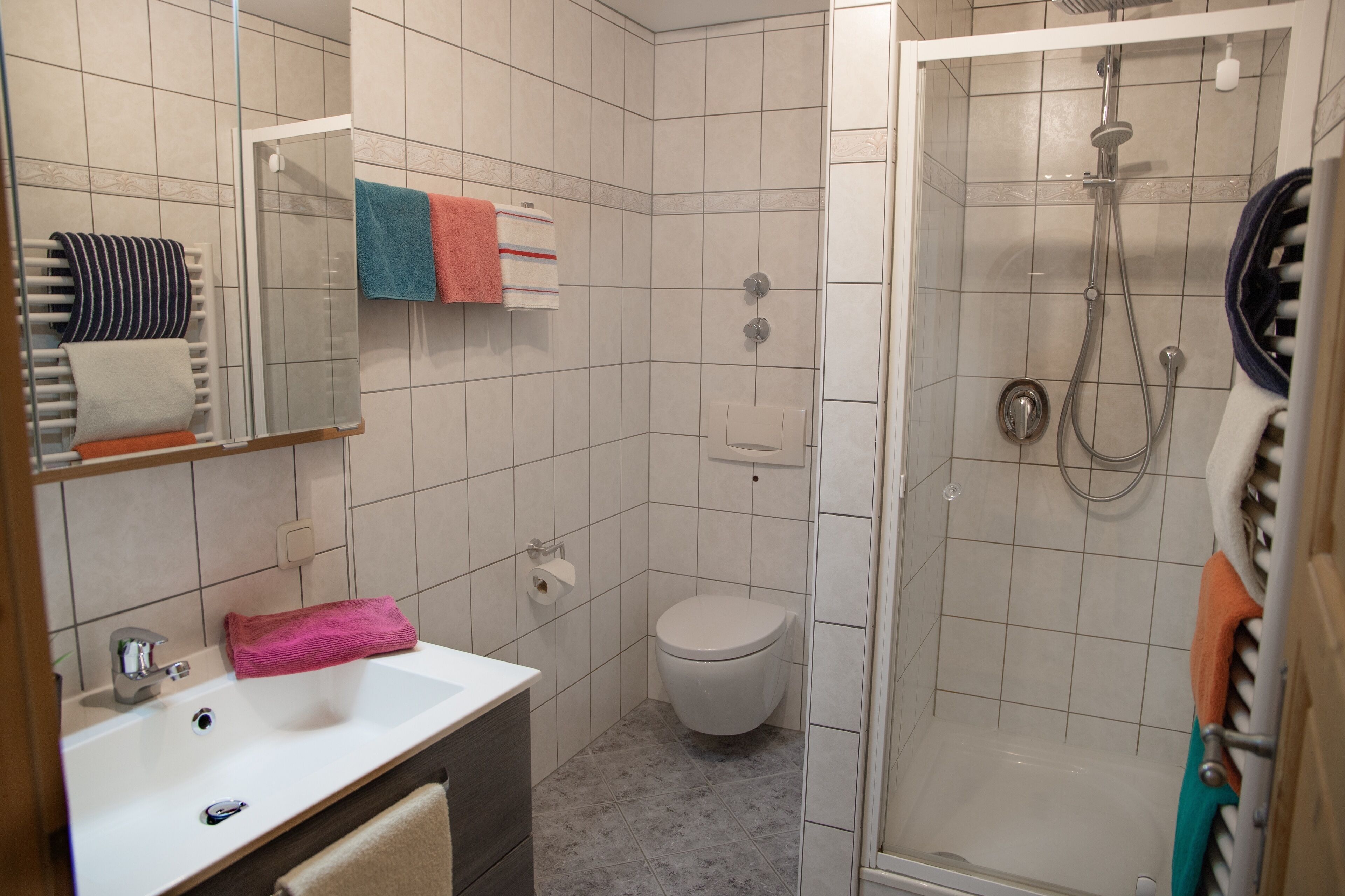 Ein Badezimmer mit Waschbecken, Spiegel, Toilette und Dusche.