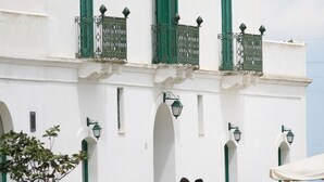 A white building with green shutters and balconies, featuring arched doorways and decorative lanterns. - Golf Club Metaponto (Bernalda)