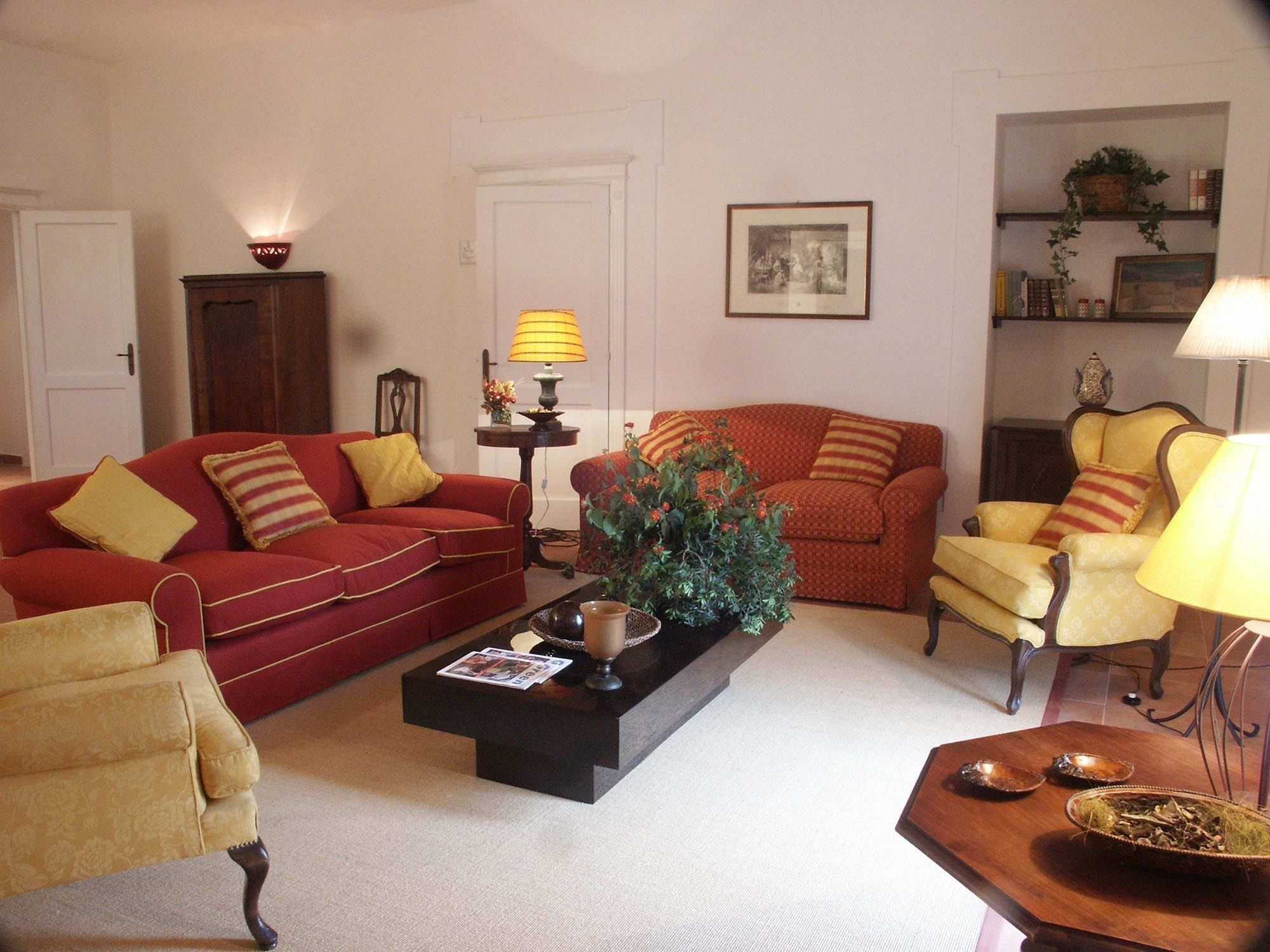 A living room with a red sofa, yellow armchair, and a coffee table with a plant.