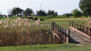 A wooden bridge leading to a golf course with a clear sky and distant power lines. - Golf Club Metaponto (Bernalda)