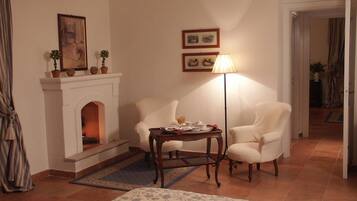 Una habitación con chimenea, dos sillones, una mesita con lámpara y una alfombra estampada.