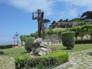 A statue in a park with a stone wall and trees in the background. - Hotel Avenida (Baiona)