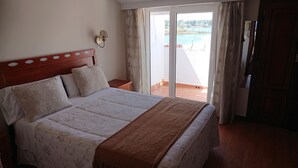 Ein Hotelzimmer mit Bett, Nachttisch, Wandlampe und Blick auf einen Pool durch eine Glastür.
