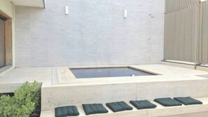 A modern outdoor pool area with a rectangular pool, a stone ledge with cushions, and a potted plant. - Copa Loft (Rio de Janeiro)