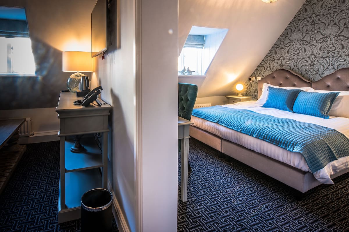 Habitación compacta y bien iluminada con cama, escritorio y una ventana pequeña.
