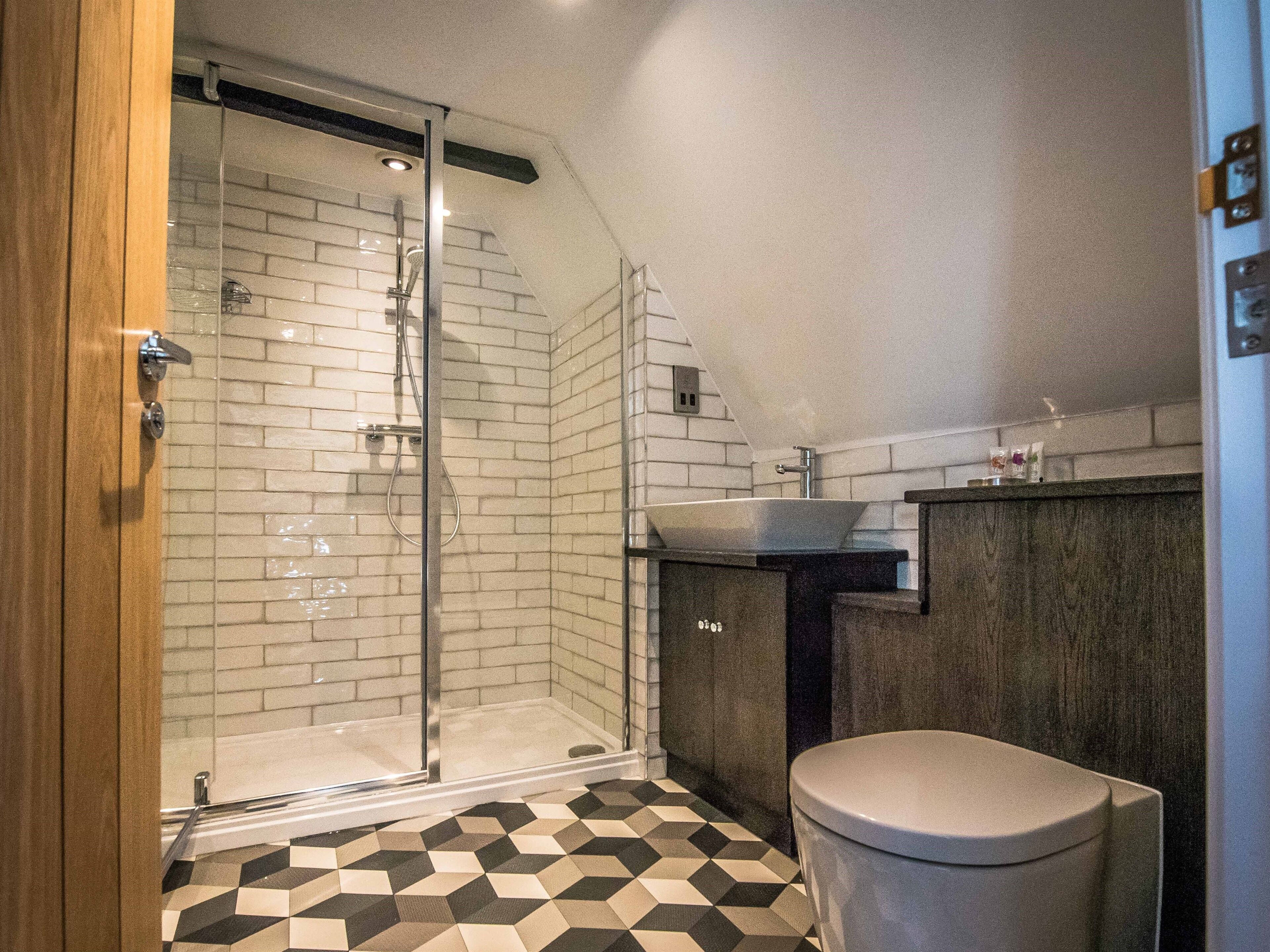 A bathroom with a glass shower enclosure, a toilet, and a sink.