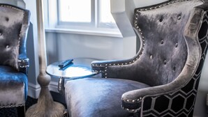 A room with two upholstered chairs with metallic studs, a small round table, and a window providing natural light. - The Royal Standard (Ely)