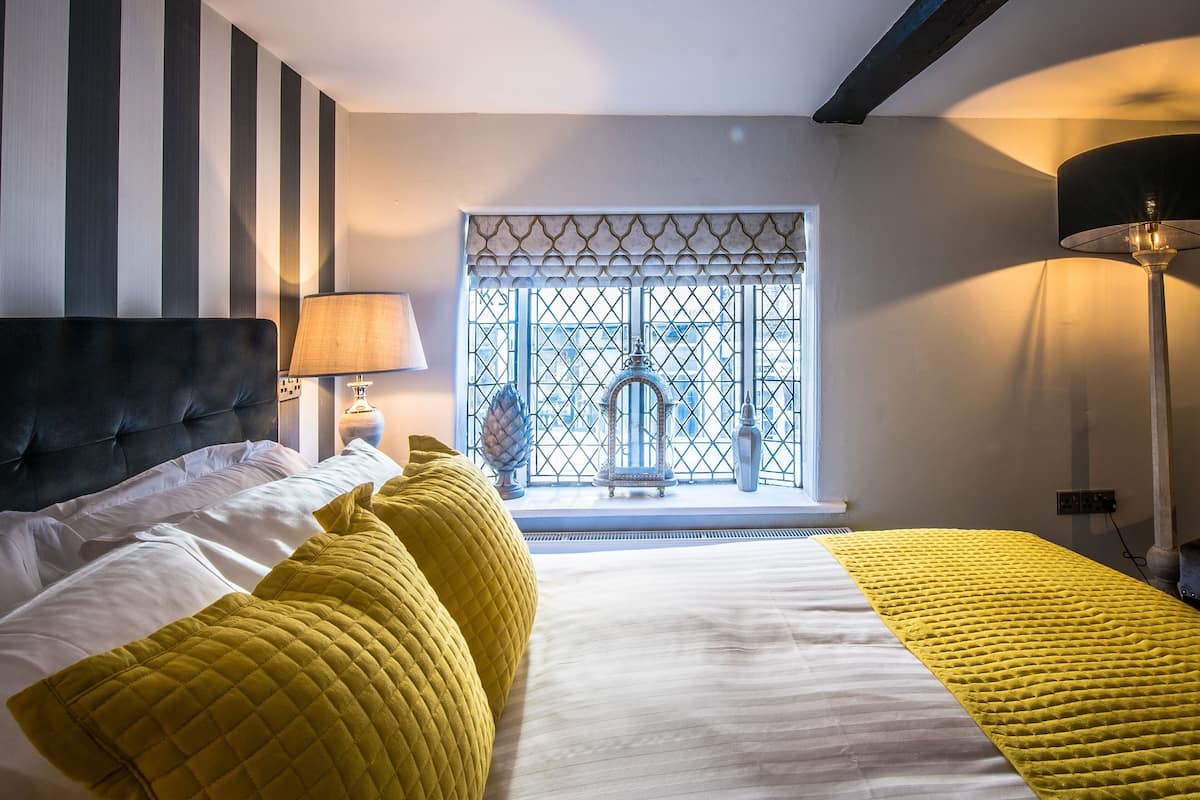 Habitación de hotel con una cama, una lámpara, una ventana con vistas y un adorno en el alféizar.