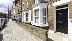 A row of terraced houses with white-framed windows and a brick facade. - Greyhound Road Rooms (London)