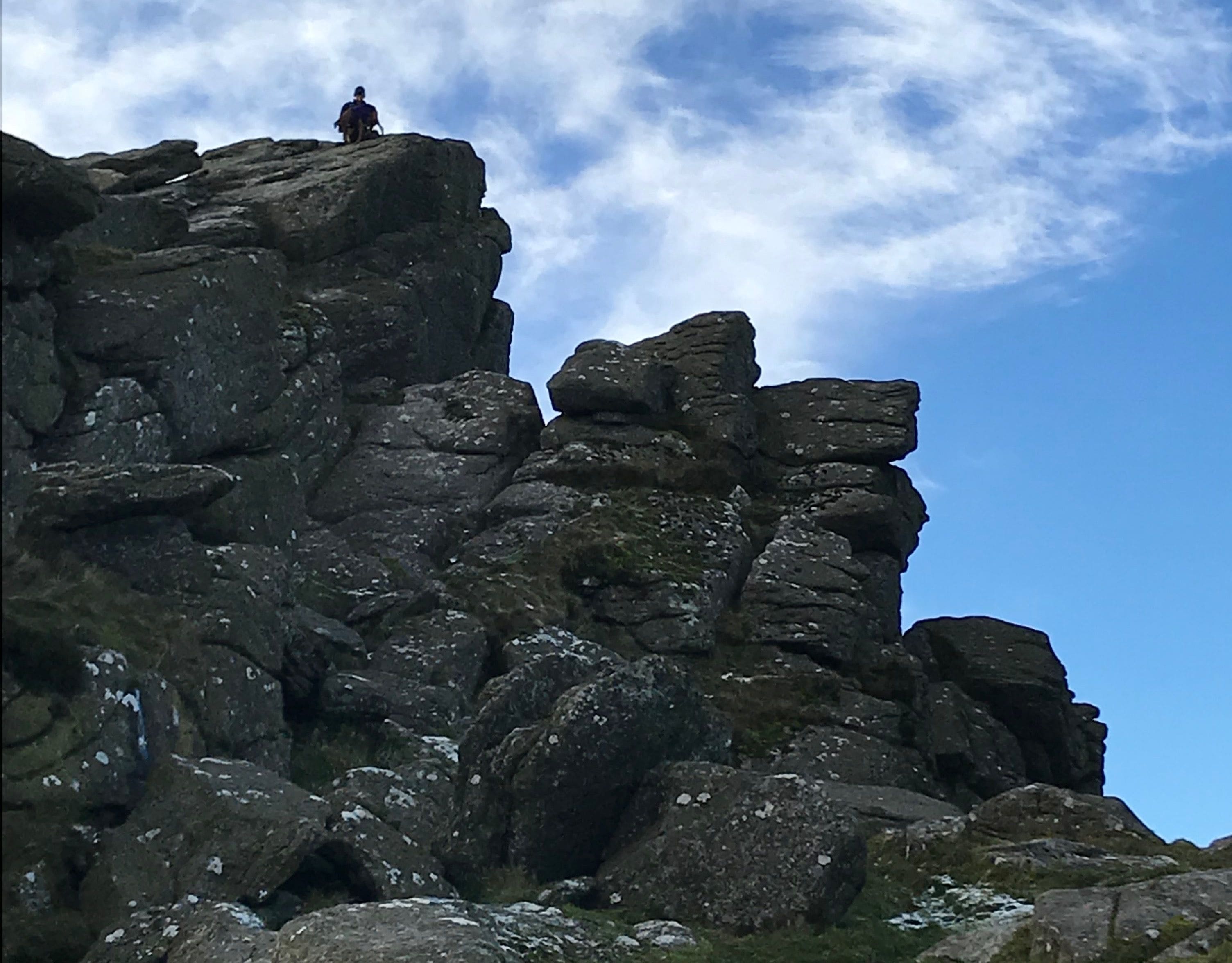 A rocky mountain peak with a person standing at the top.