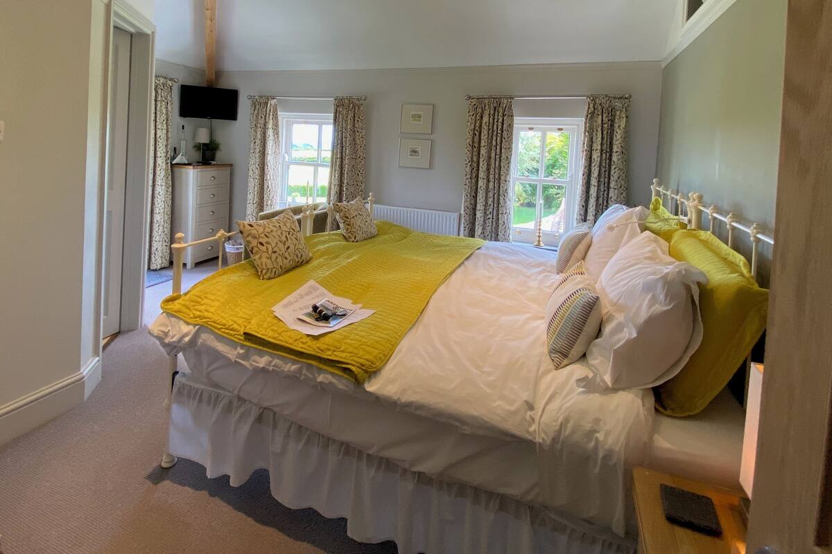 A bedroom with a bed, bedside table, lamp, and a window with curtains.