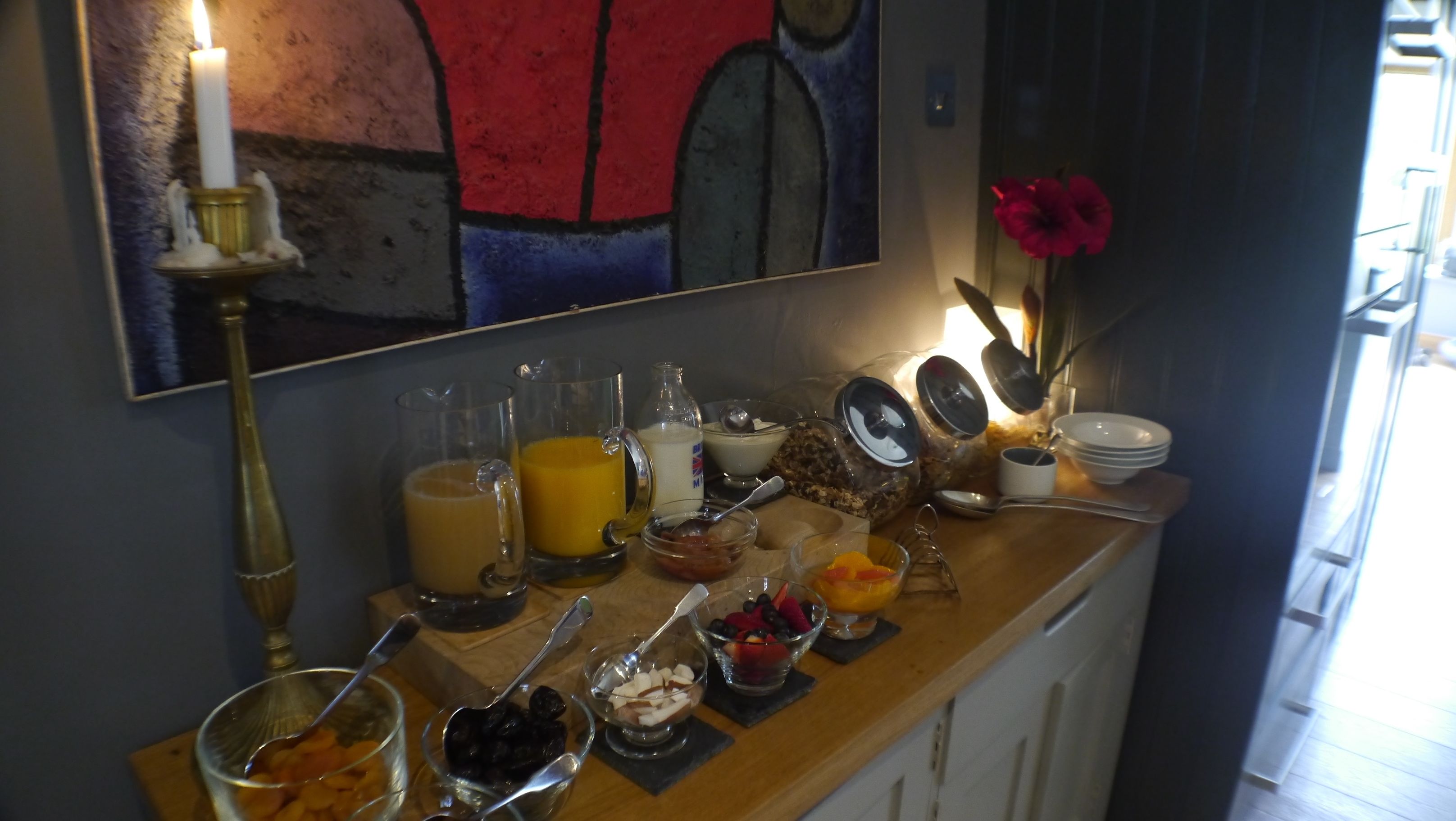 A breakfast buffet with various food items and drinks on a wooden counter.