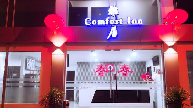 Ingresso di un hotel Comfort Inn con insegna al neon, ampie finestre e lanterne rosse.