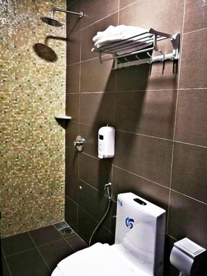 A bathroom with a shower, toilet, and towel rack.