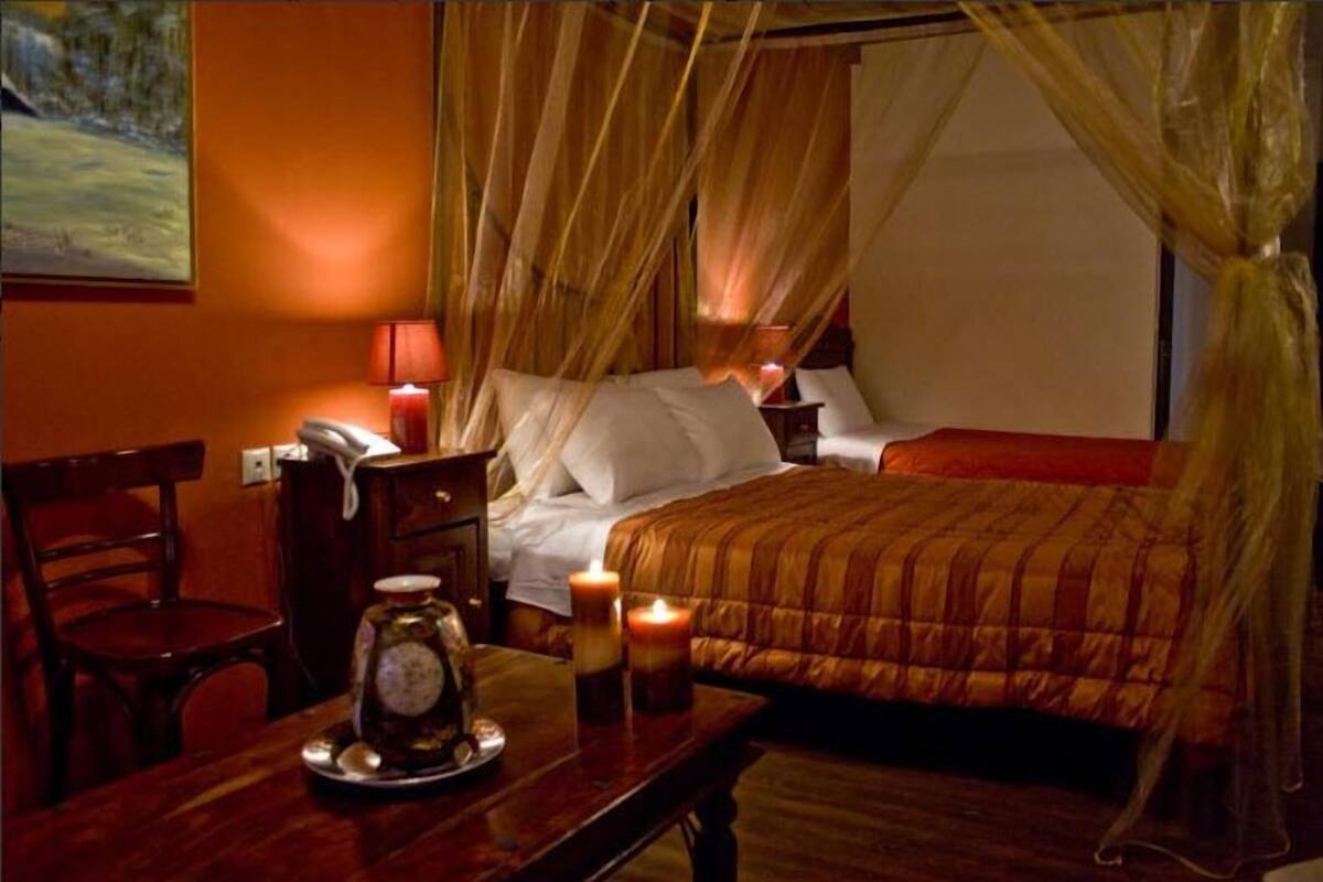 Habitación de hotel con cama, mesita de noche con lámpara, una silla y un adorno sobre la mesa.