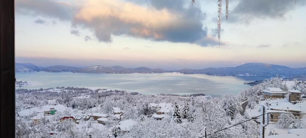 Ein weitreichender Blick auf eine verschneite Landschaft mit einem See und fernen Bergen.