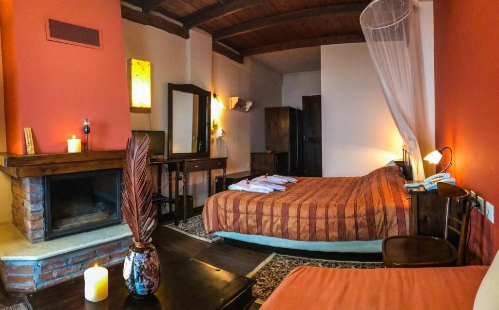 Una habitación acogedora con chimenea, una cama con dosel, un escritorio con silla y un espejo en la pared.