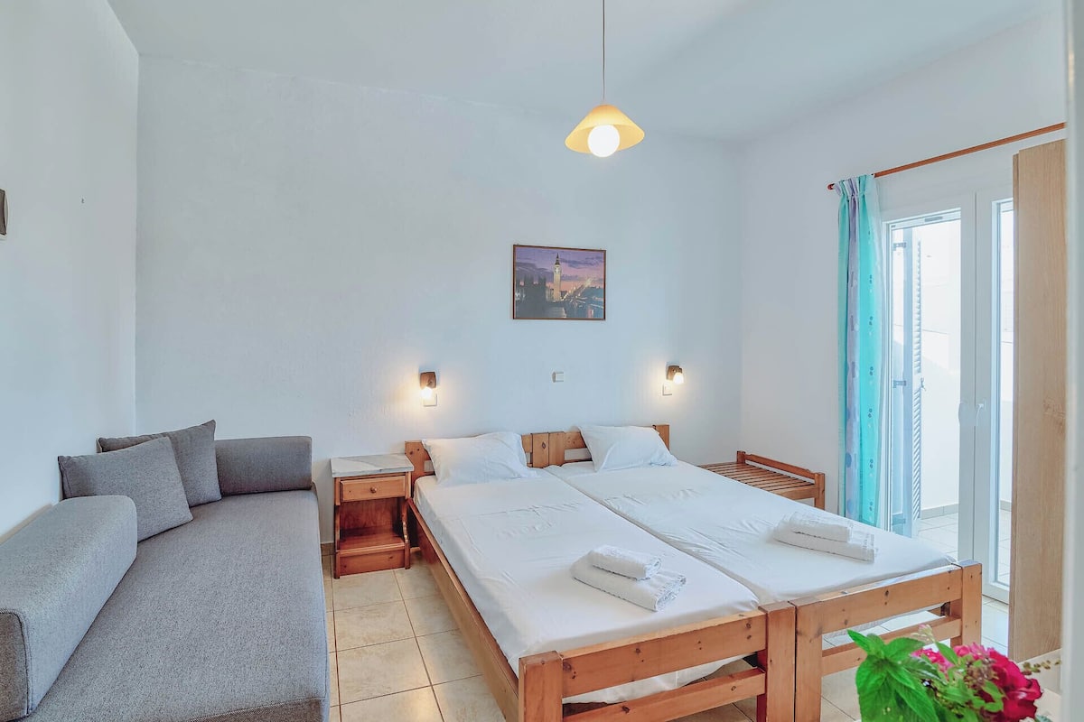 Un dormitorio con cama, sofá, mesita de noche y un cuadro colgado en la pared.