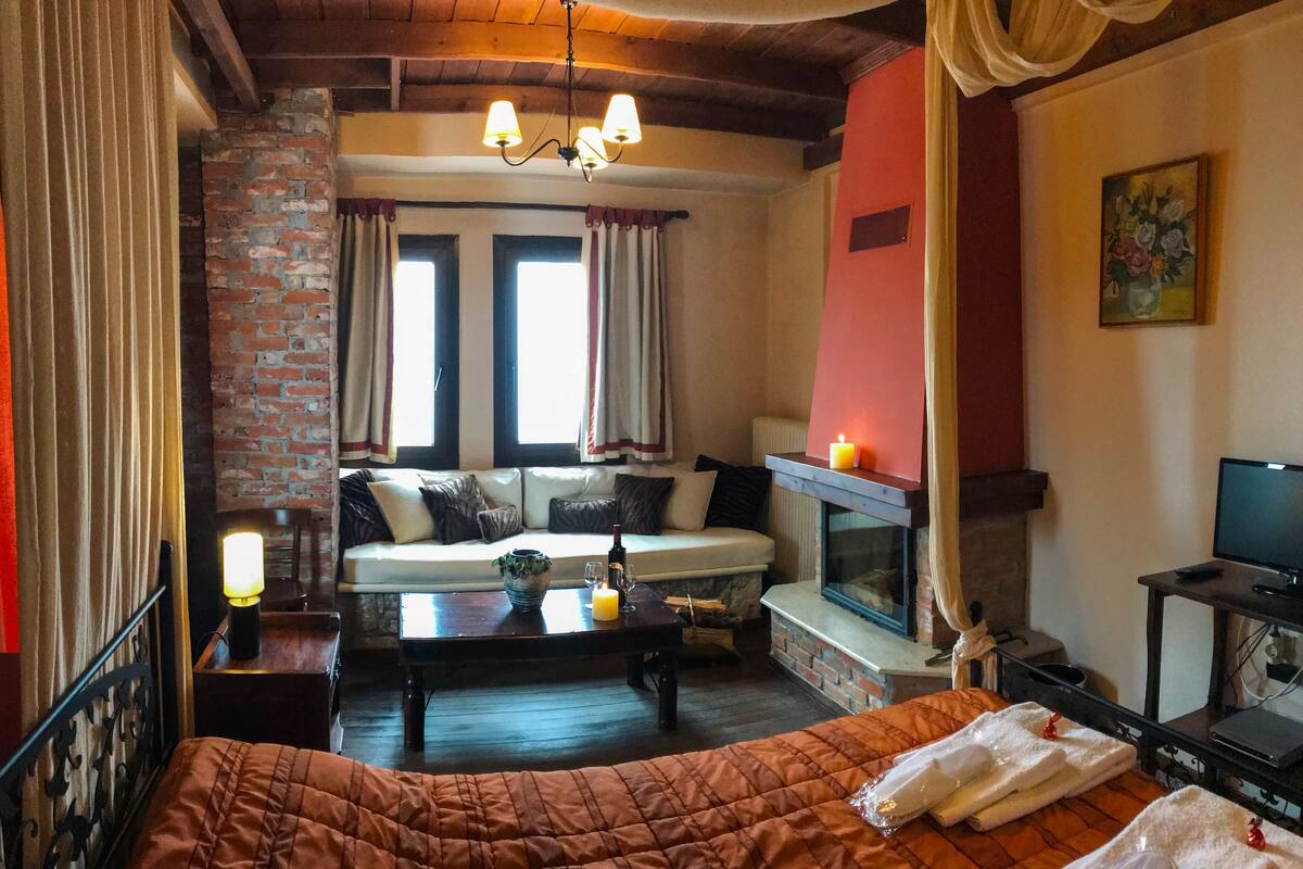 Una habitación acogedora con una cama, un sofá, una chimenea y un televisor.