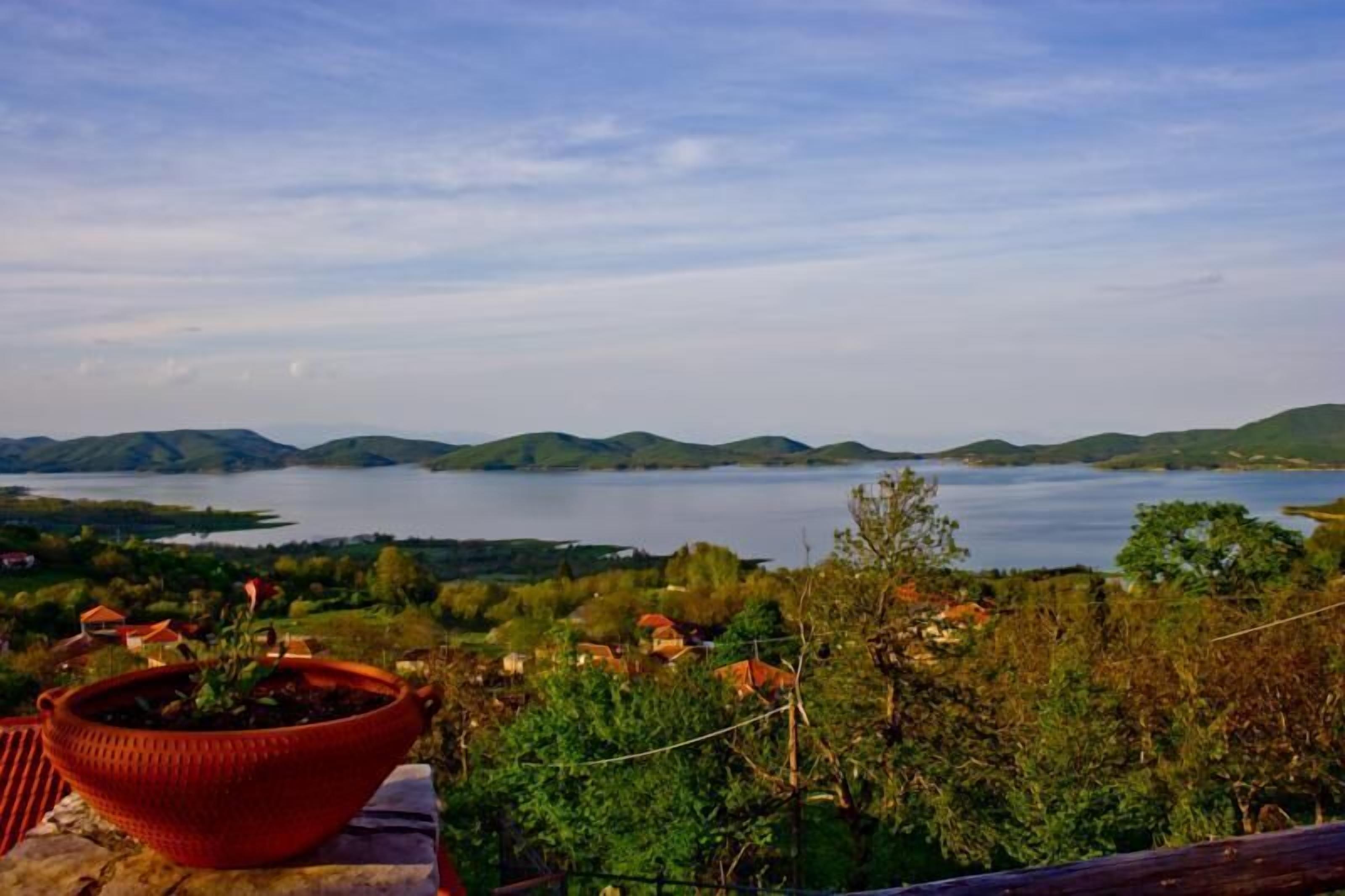 Vista panorámica de un lago rodeado de colinas y una olla roja en un saliente.