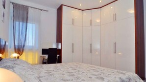 A bedroom with a large bed, a desk, and a wardrobe. - Holiday apartment with terrace and air conditioning (Zadar)