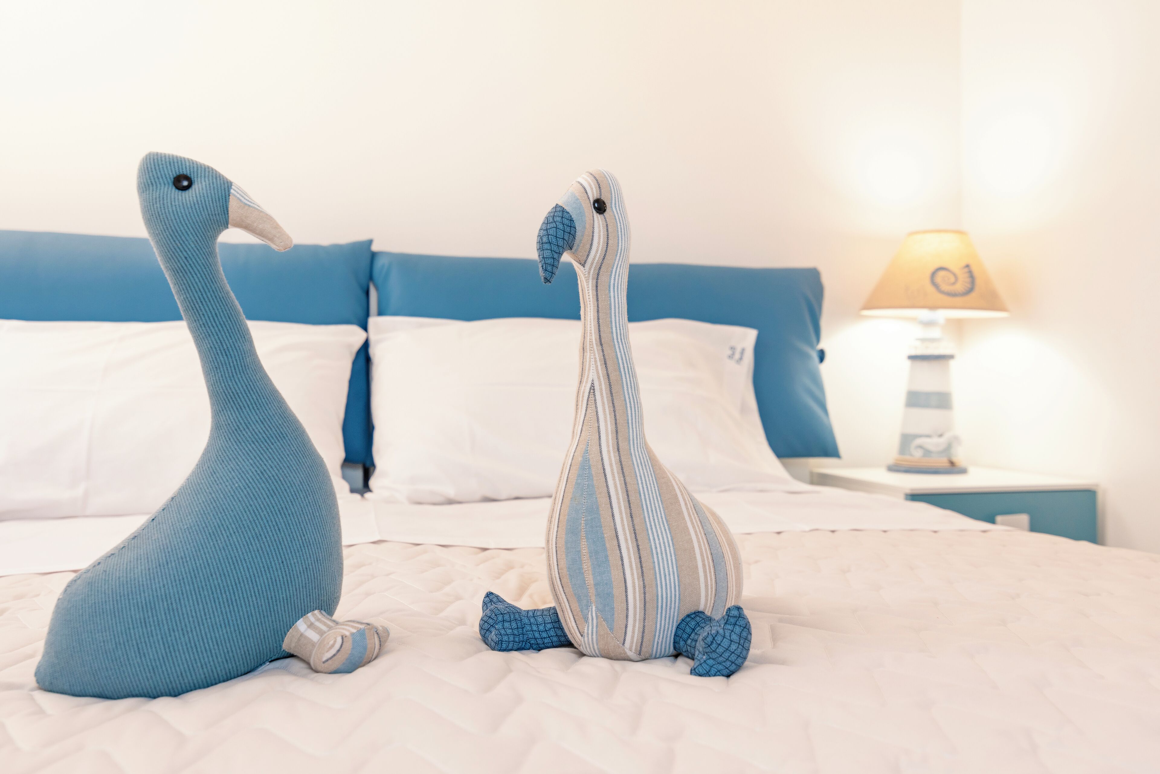 A bed with two plush animal pillows, a bedside table with a lamp, and a blue headboard.