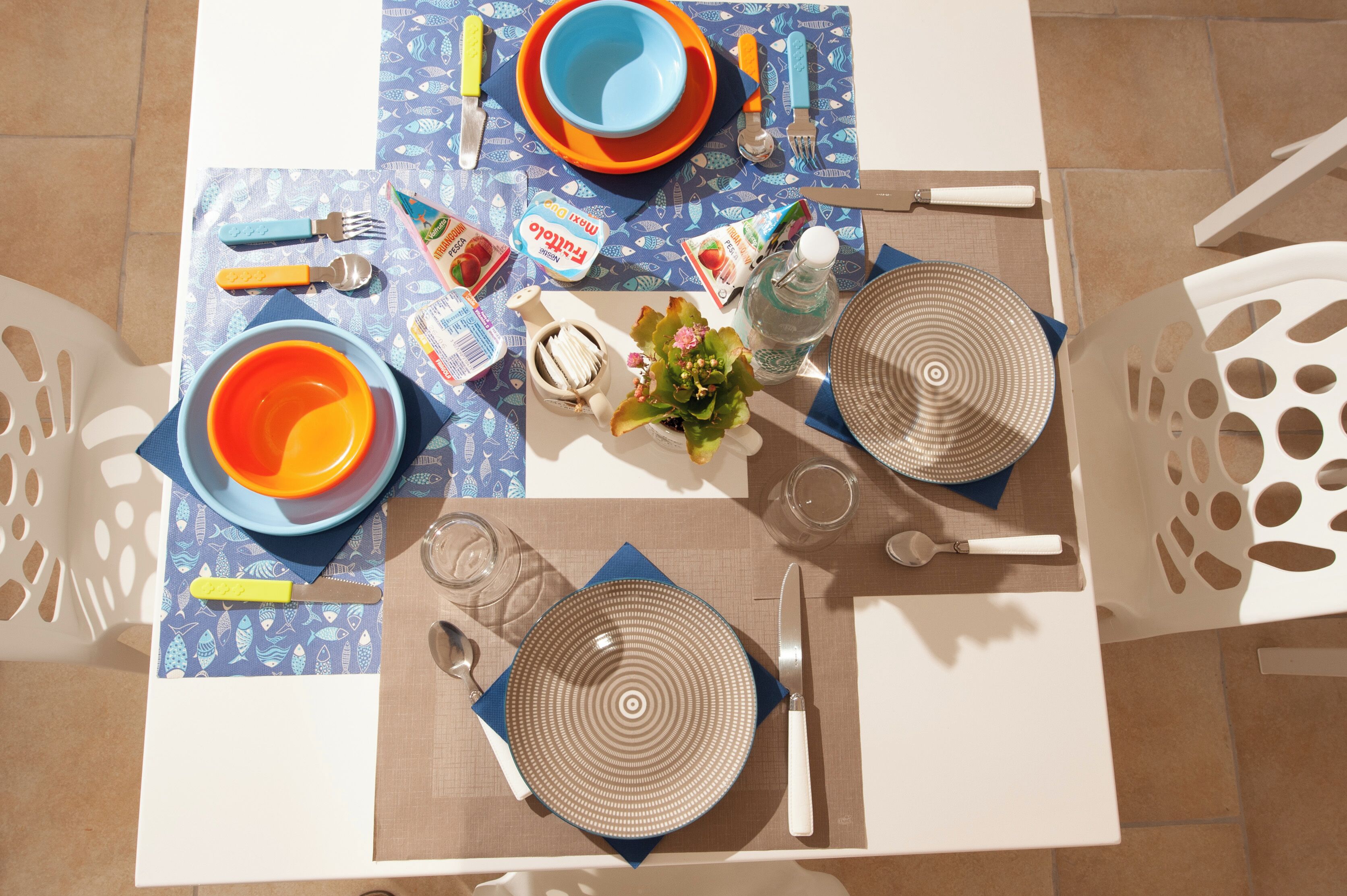Una mesa de comedor dispuesta con platos, tazones, cubiertos y aderezos.