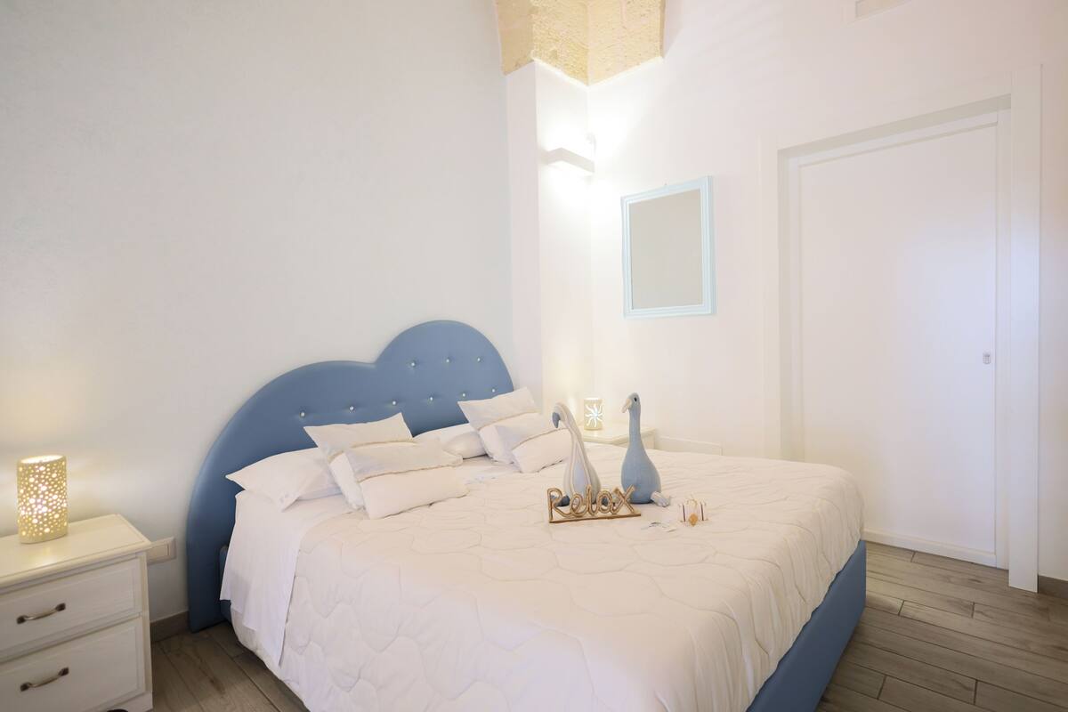 Un dormitorio con cama, mesita de noche, lámpara de pared e iluminación mural.