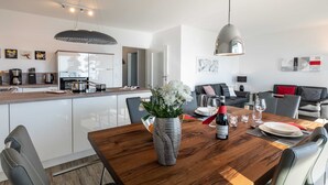 Eine moderne Küche mit weißen Schränken, einem Holztisch und einer Blumenvase.