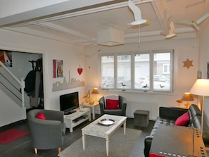 Ein modernes Wohnzimmer mit einem Flachbildfernseher, zwei Sofas, einem Couchtisch und einer Treppe.
