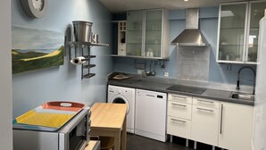 A compact kitchen with a dishwasher, oven, and sink. There is a wooden table and a painting on the wall. - Pleasant house with terrace at 300 m from the sea  (Sangatte)