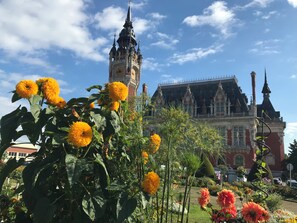 Un bâtiment historique doté d’une tour horlogée et d’un jardin fleuri.