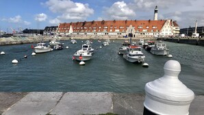 A harbor with multiple boats docked, a large building with a red roof, and a lighthouse in the background. - Pleasant house with terrace at 300 m from the sea  (Sangatte)