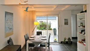 A dining area with a table set for four, a lamp, and a view of the garden through a glass door. - Pleasant house with terrace at 300 m from the sea  (Sangatte)