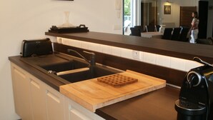 A modern kitchen with a dark countertop, a sink, and a wooden cutting board.