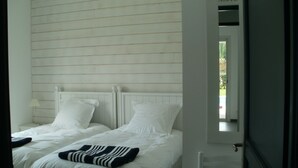 A bedroom with two beds, white bedding, and a wooden headboard.