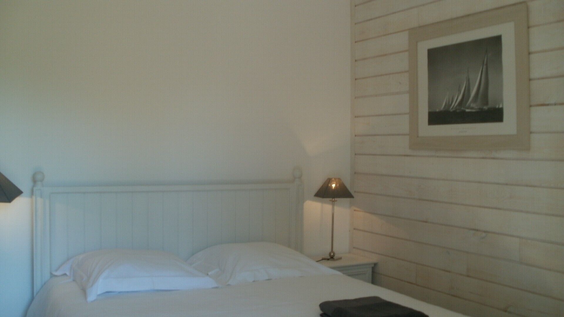 Une chambre à coucher avec un lit, une table de chevet avec une lampe et un tableau encadré au mur.
