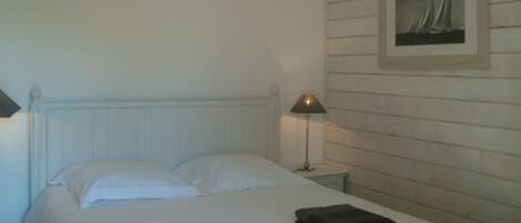 Une chambre à coucher avec un lit, une table de chevet avec une lampe et un tableau encadré au mur.