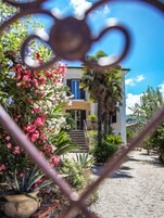 Una casa con jardín delantero, una escalera que lleva a la entrada, y un cielo azul despejado.