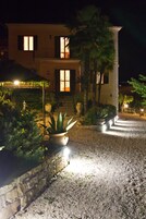 Un edificio de dos pisos con un muro de piedra y plantas en macetas al frente.