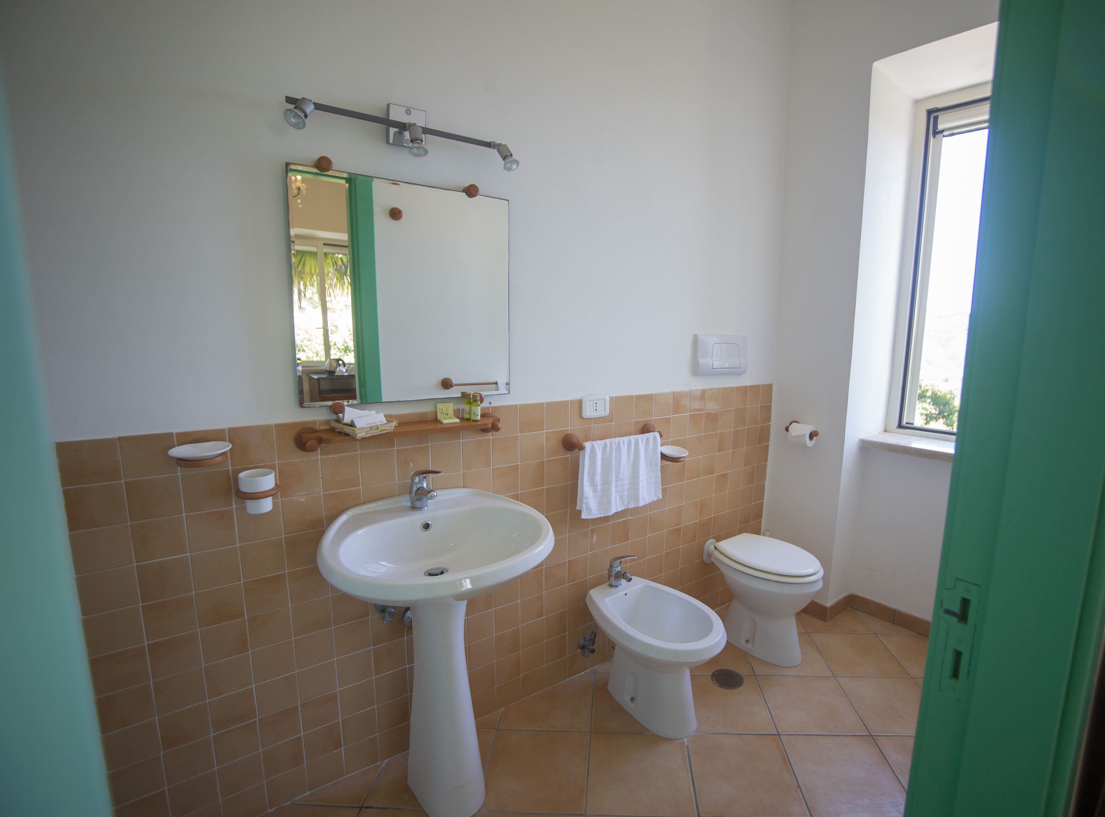 Un bagno con lavandino, bidet, water e specchio.