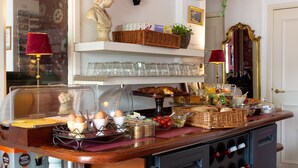 A breakfast bar with a variety of food items, a clock, and a bust sculpture. - Amsterdam House Hotel (Amsterdam)