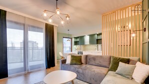 A modern living room with a grey sofa, a round coffee table, and a large window with sheer curtains. - City Center Apartments SPA & Wellness by Apartmore (Gdansk)