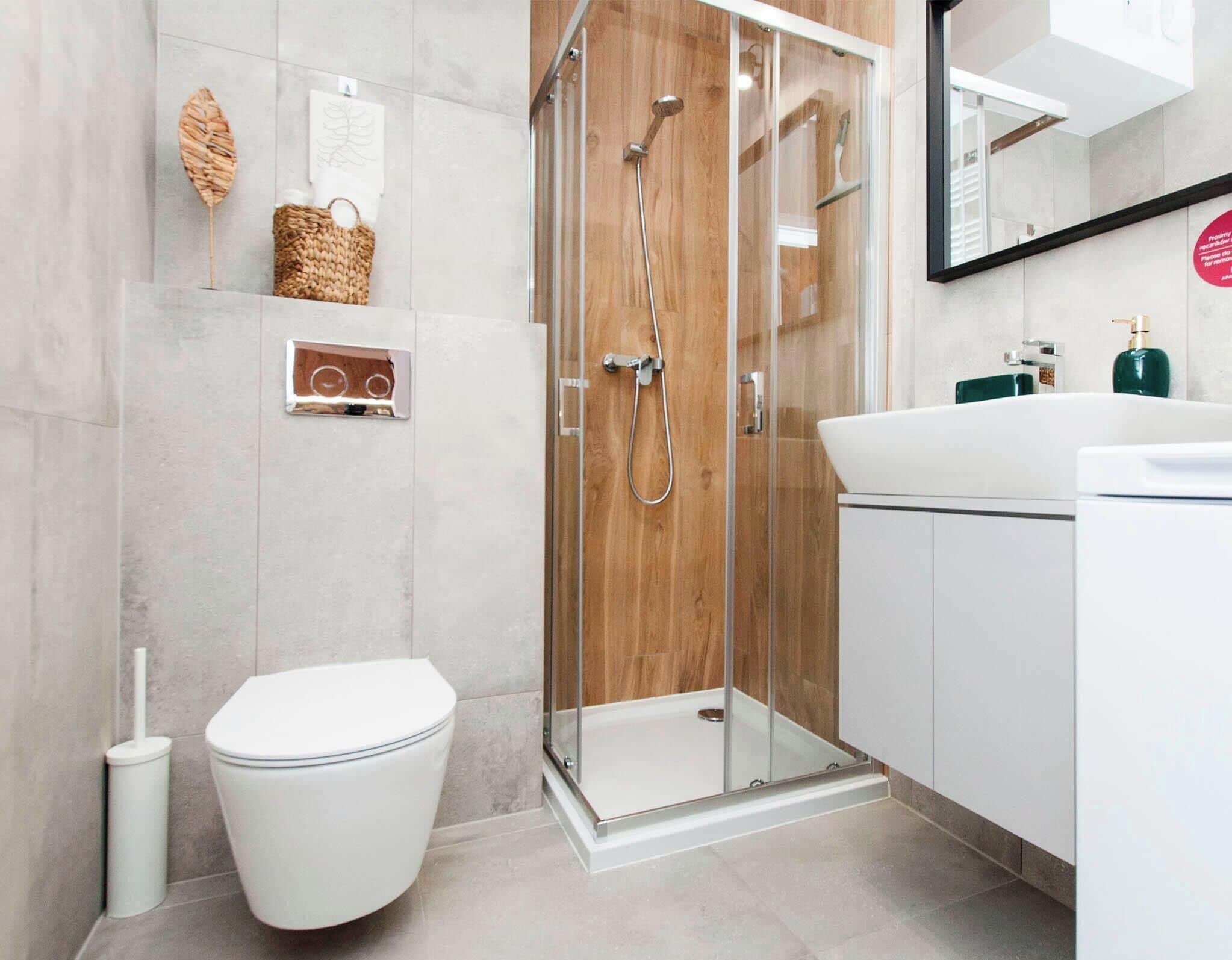 A modern bathroom with a glass-enclosed shower, a white toilet, and a sink with a mirror above it.