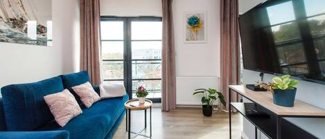 Una sala moderna con un sofá azul, un televisor de pantalla plana y una mesita con plantas.