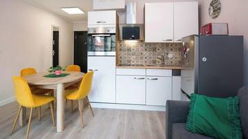 A compact kitchen with a dining table, chairs, and a refrigerator.